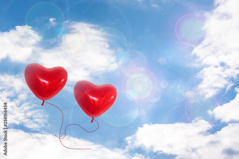 Two Red hearts balloons flying in the blue sky