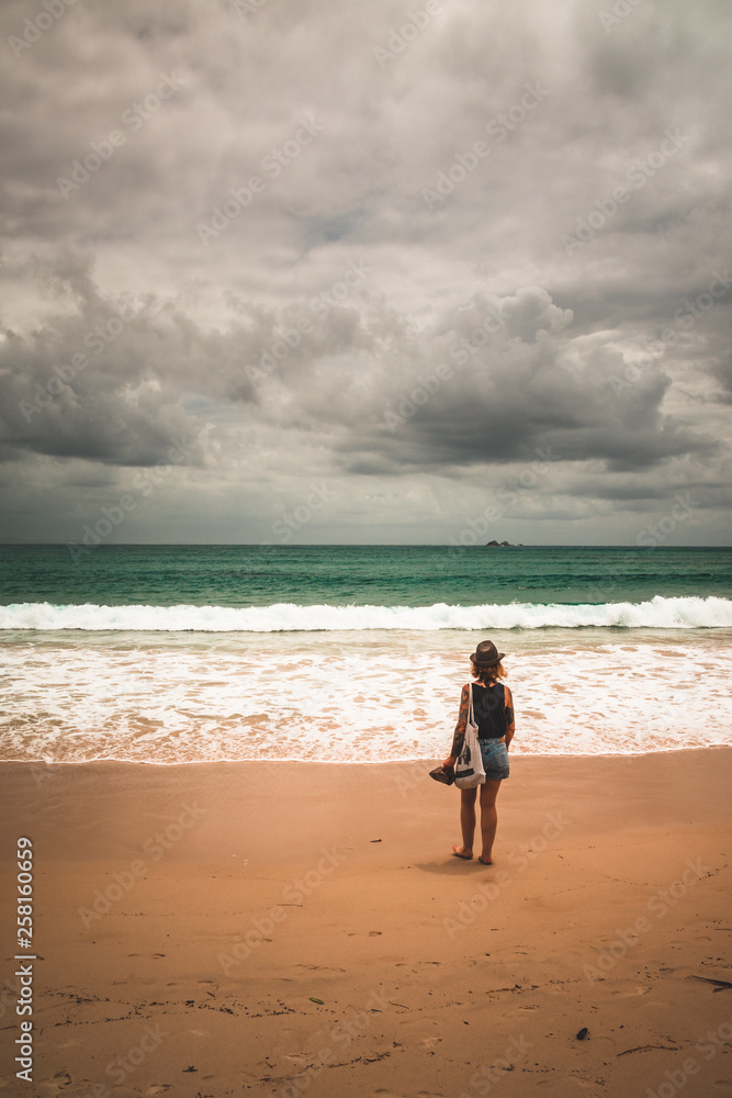 junge Frau mit Sandalen in der Hand stehend am Sandstrand