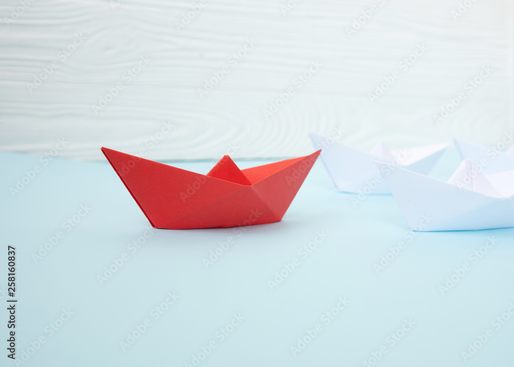 Leadership concept. Red leader paper ship leading among white on blue background. Leadership concept. Red leader paper ship leading among white on blue background.