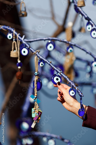 Image of amulets on tree and woman's hand.