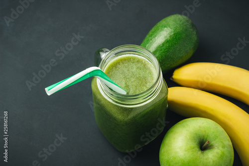 Green, healthy, detox smoothie from avocado, banana, apple in mason jar on dark background, vegetarian food
