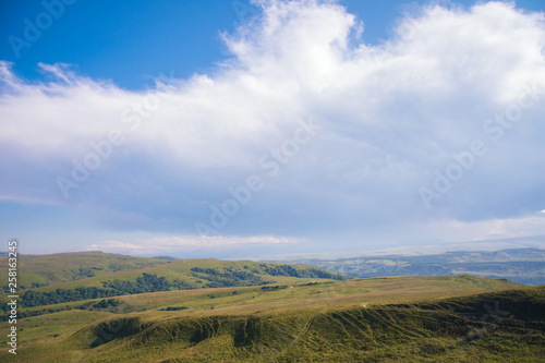 A huge panorama of the impending huge dark blue clouds over the mountains and hills in the summer