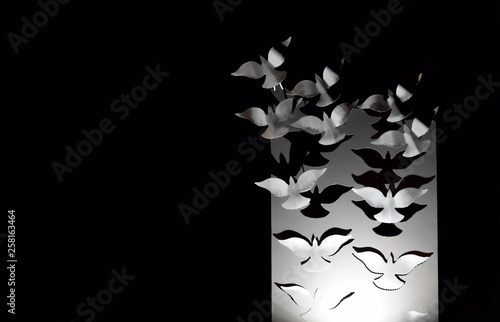 White doves flying away into the dark from a white stand - a beautiful postcard with negative space.