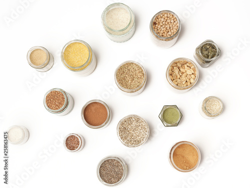Top view of jars with grains, seeds, legumes, flours and various food ingredients. Healthy food concept.
