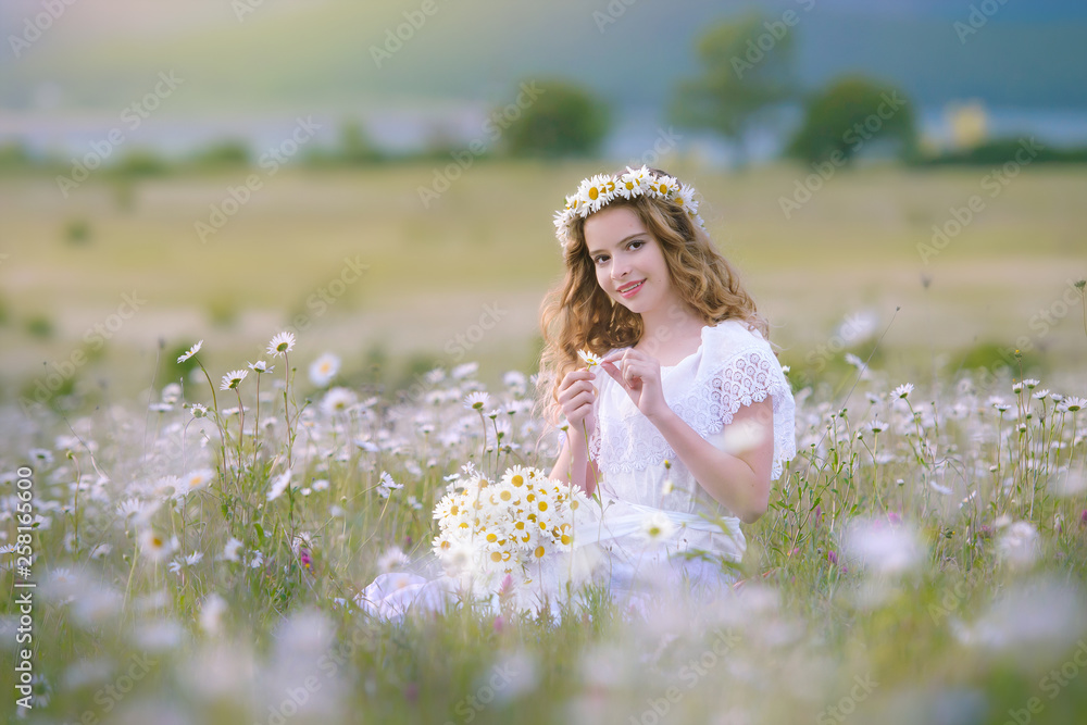 A young girl on a green field of chamomile . A young girl on a green field of chamomile .
