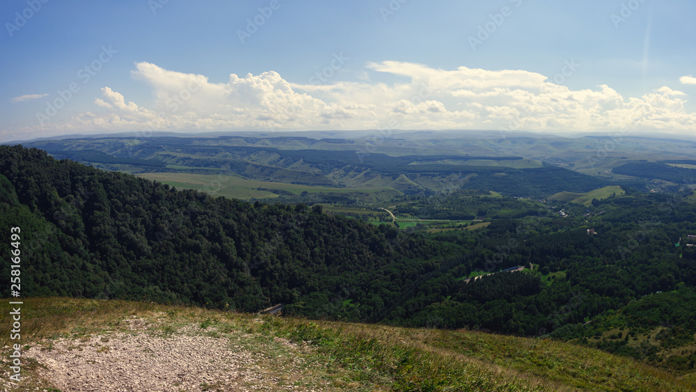 A huge panorama of the impending huge dark blue clouds over the mountains and hills in the summer