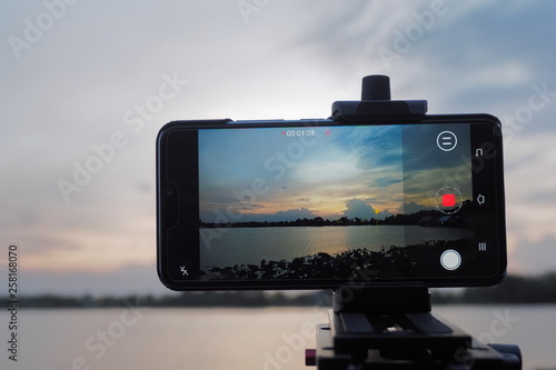 view of android smart phone recording VDO4K and shooting timelapse with sunset on the lake show on monitor, Krajub reservoir, Banpong, Ratchaburi, Thailand.