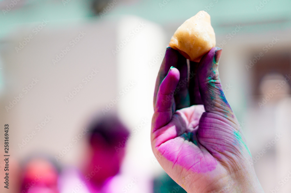 Colorful hand on holi holding a Samosa showing the food and delicacies on holi Colorful hand on holi holding a Samosa showing the food and delicacies on holi