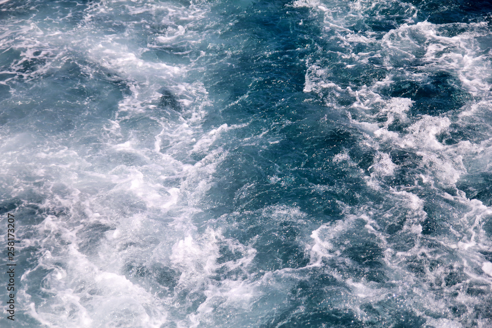 Turbulence made by foam of sea water from a high-speed yacht on surface of sea. Blue sea waves with lot of sea foam. Surface of sea with waves, splash, foam and bubbles, blue background and wallpaper. Turbulence made by foam of sea water from a high-speed yacht on surface of sea. Blue sea waves with lot of sea foam. Surface of sea with waves, splash, foam and bubbles, blue background and wallpaper.