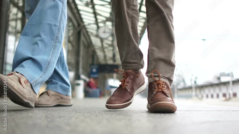 Unrecognizable man and woman walking along the platform with a suitcase. Casual style, travel concept and transportation Unrecognizable man and woman walking along the platform with a suitcase. Casual style, travel concept and transportation