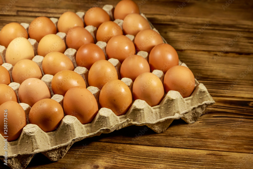 Raw chicken eggs in cardboard pack on wooden table Raw chicken eggs in cardboard pack on wooden table