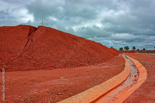 Large piles of bauxite ore, which is refined into aluminum, sit at a treatment area storage of bauxite. Guinea, Africa.