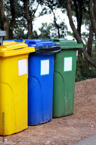Trash can, garbage bin, recycling bin in tourist complex resort, waiting to be picked up by garbage truck. Blue, yellow and green containers for waste sorting, sort garbage for metal, paper and glass. © zoranlino
