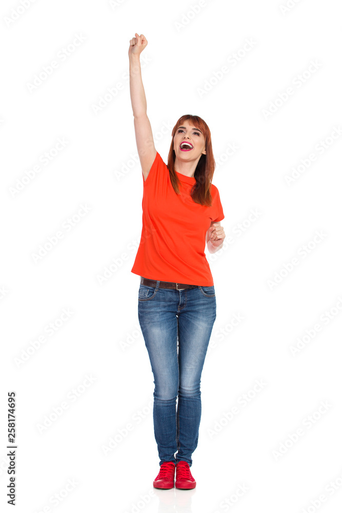 Happy Young Woman Is Standing With Arm Raised And Cheering Happy Young Woman Is Standing With Arm Raised And Cheering