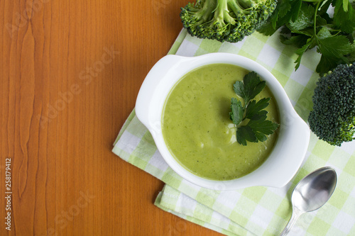Vegetarian broccoli puree soup in th white bowl on the light brown wooden background.Top view.Copy space.