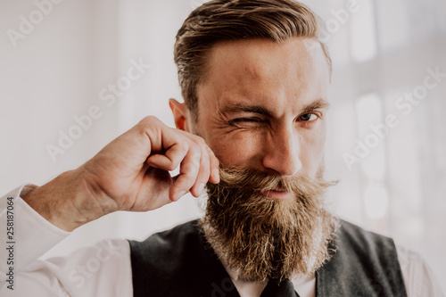 Handsome bearded hipster playing with his mustaches