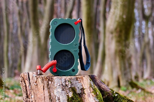 Portable Bluetooth Speaker on a tree stump in the woods photo