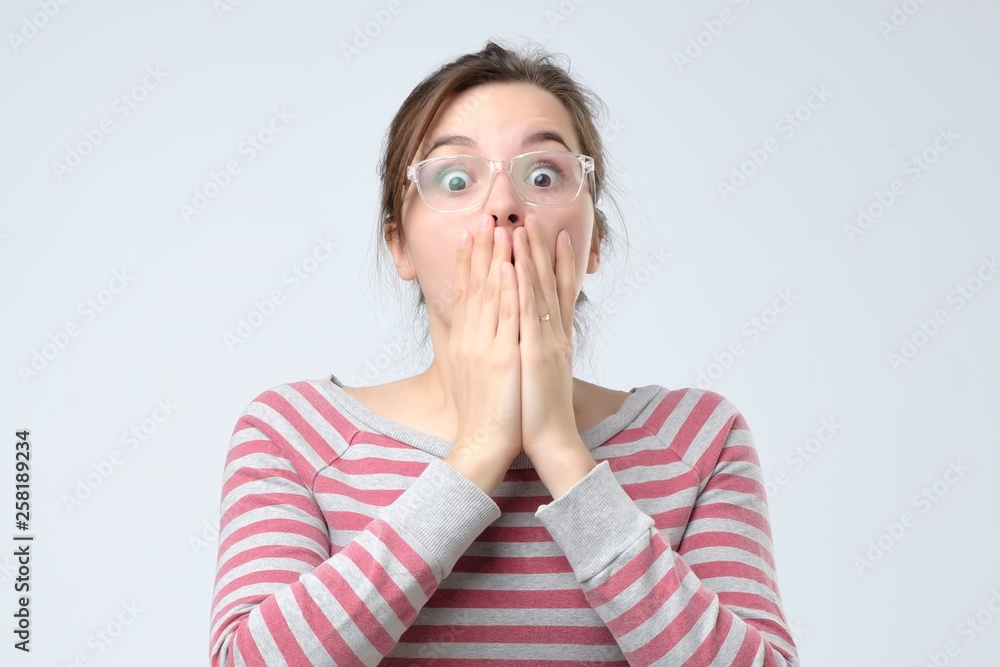 woman covering mouth with hand and staring at camera woman covering mouth with hand and staring at camera