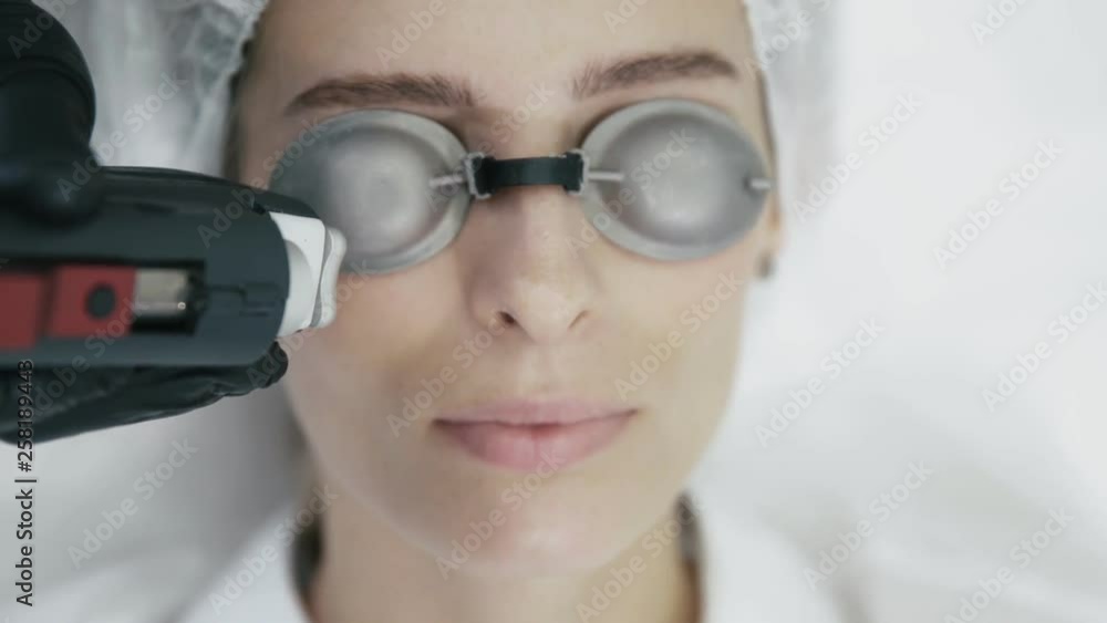 Close up cosmetologist hands with special equipment does laser procedure for removal of blood vessels on girl's face Close up cosmetologist hands with special equipment does laser procedure for removal of blood vessels on girl's face
