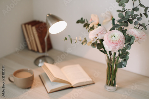 Home interior with design elements.  Wooden desk with books and flowers. Bouquet and books on white background.  Planning and design concept. Workplace. Instagram feminine flat lay. 