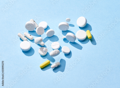 Pills and capsule falling on a blue surface photo