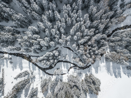 Aerial view of river thorugh snow covered forest in calm scene photo