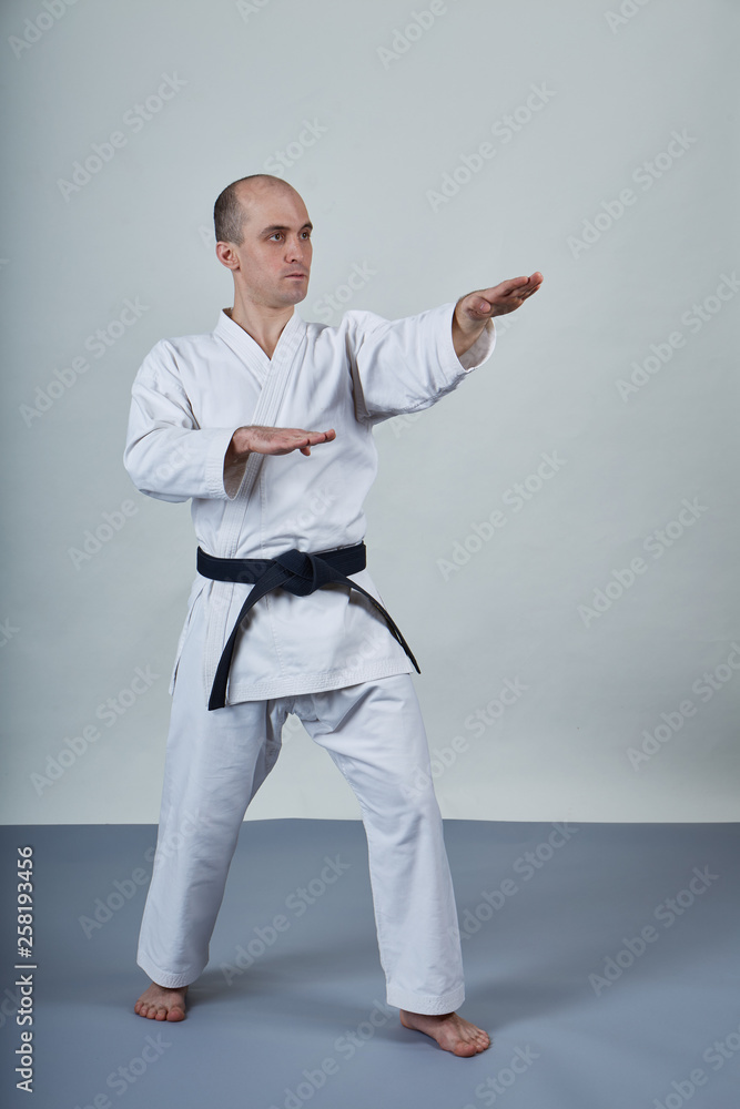 A man in karategi performs formal karate exercises on a gray cover A man in karategi performs formal karate exercises on a gray cover