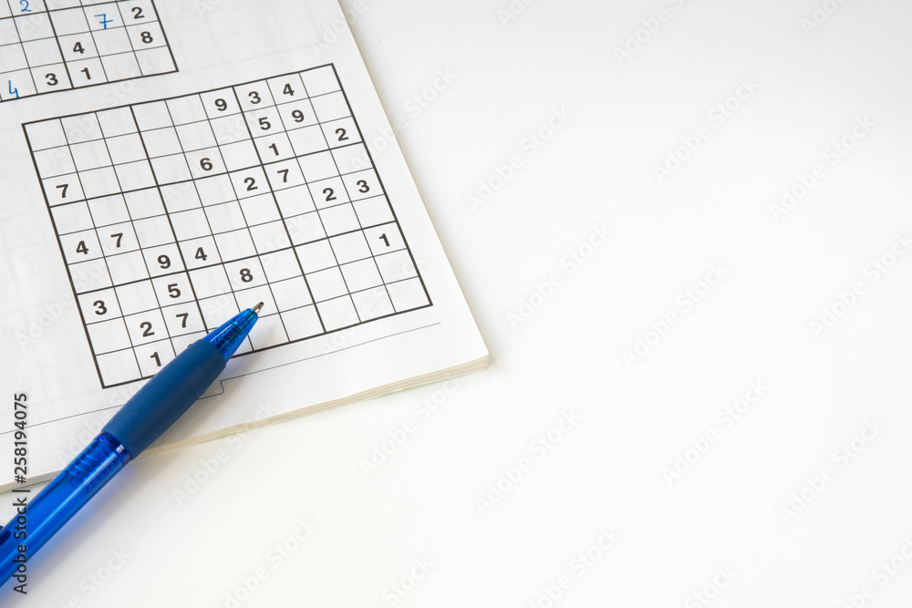 flat lay sudoku puzzle book with blue pen, against white background. space for text flat lay sudoku puzzle book with blue pen, against white background. space for text