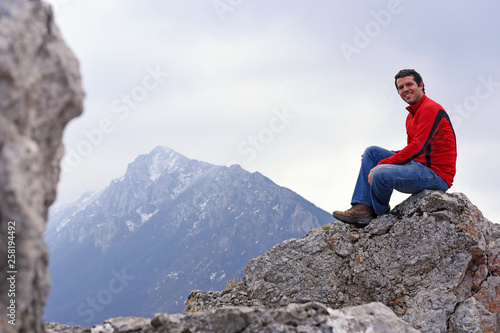 Young Man enjoy on top of the mountain. Concept of freedom, man on cliff high in mountains