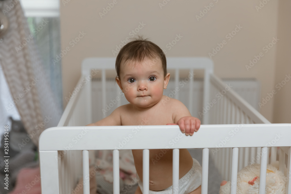 Baby girl in a diaper playing in the crib. Baby girl in a diaper playing in the crib.