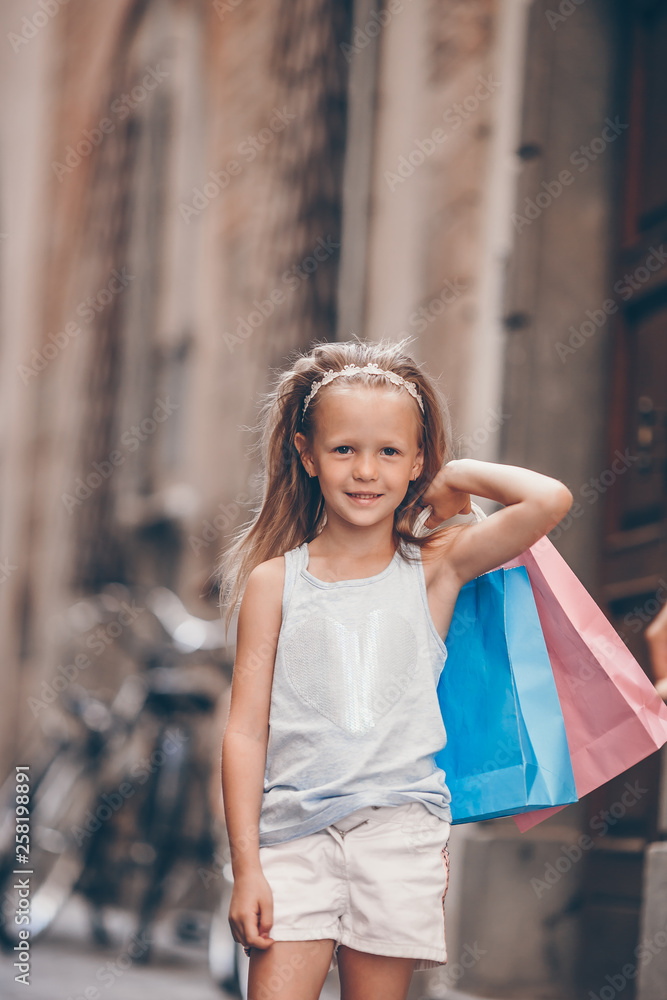 Portrait of adorable little girl walking with shopping bags outdoors in european city. Portrait of adorable little girl walking with shopping bags outdoors in european city.