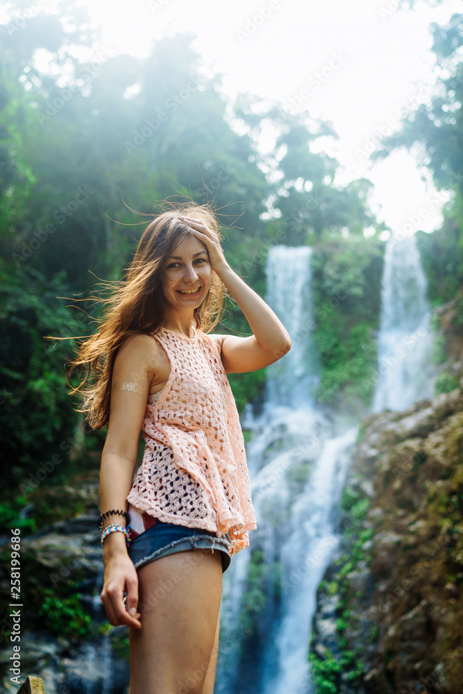 Young woman enjoying natural bathing by the Tamaraw waterfall on background. Puerto Galera, Mindoro Island, popular tourist place of Philippines Young woman enjoying natural bathing by the Tamaraw waterfall on background. Puerto Galera, Mindoro Island, popular tourist place of Philippines
