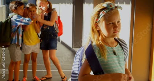 Schoolkids bullying a sad girl in hallway of elementary school 4k photo