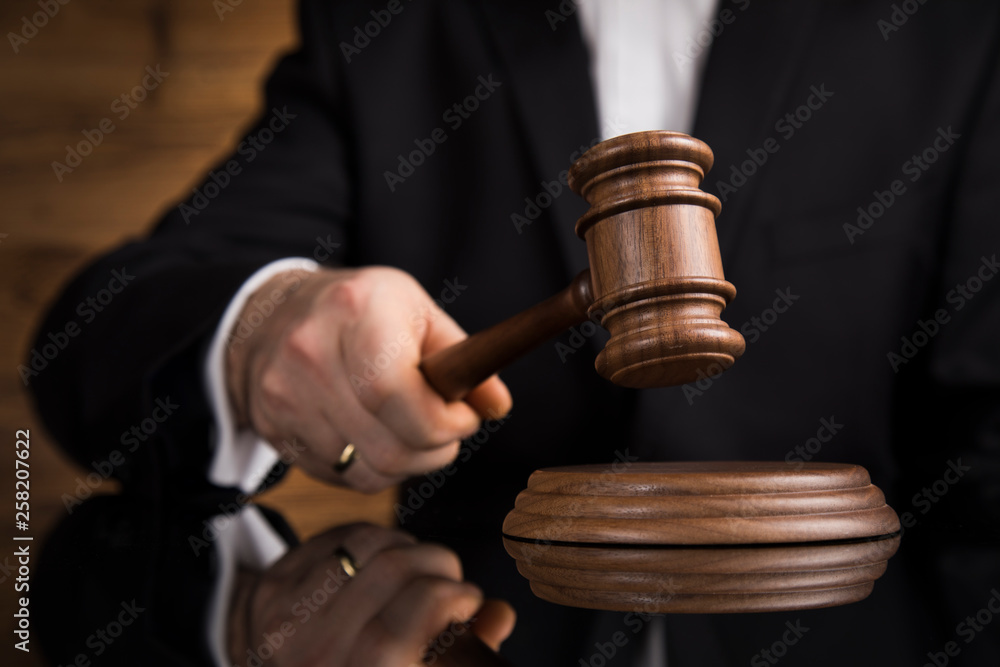 Judge, male judge in a courtroom striking the gavel Judge, male judge in a courtroom striking the gavel