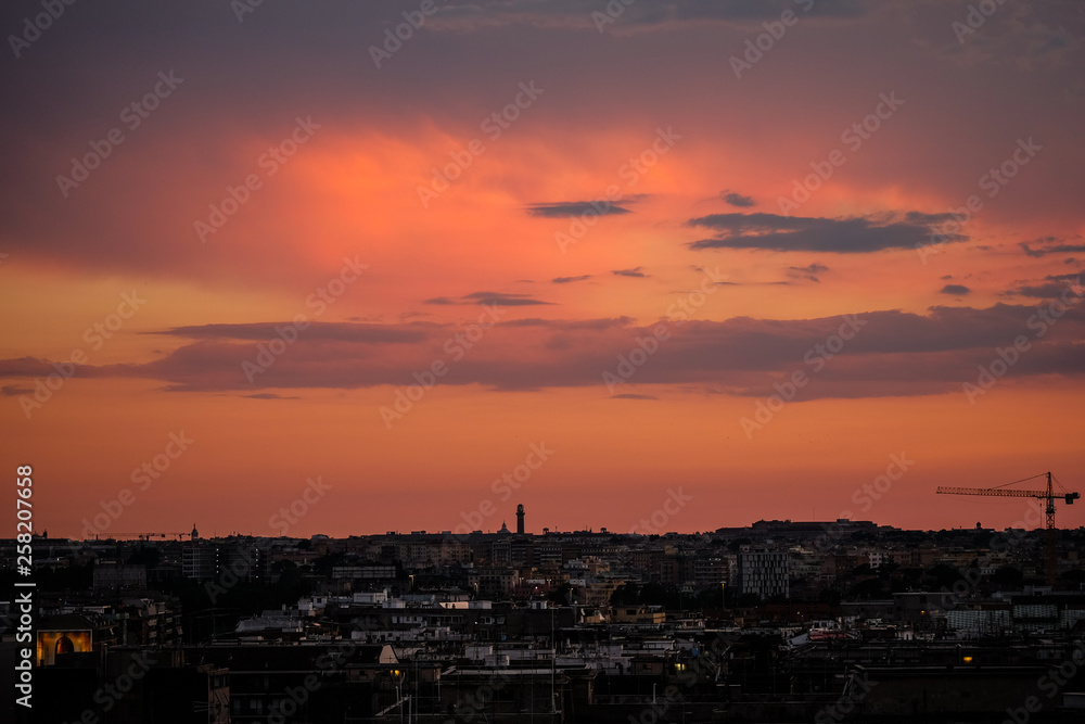 Burning red  sky on rome architecture skyline with working cranes