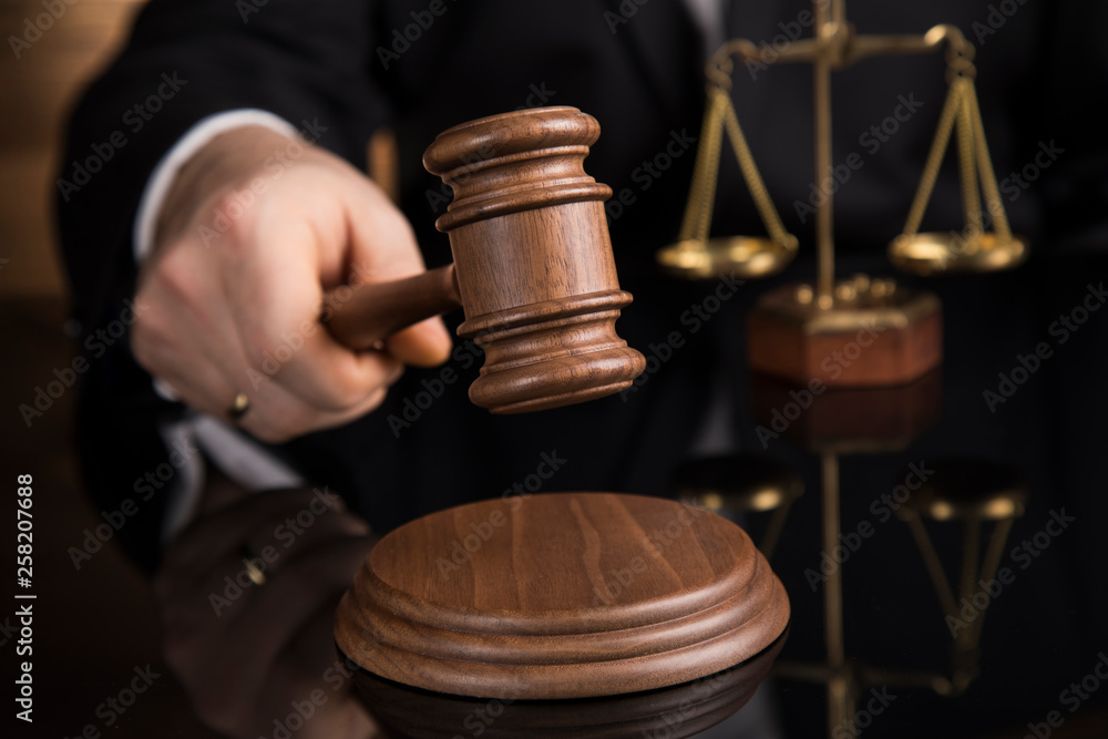 Judge, male judge in a courtroom striking the gavel Judge, male judge in a courtroom striking the gavel