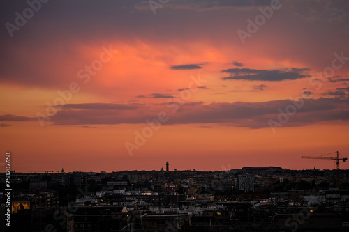 Burning red sky on rome architecture skyline with working cranes