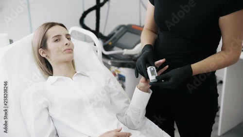 Doctor measures pressure and puls of patient with tonometer on finger before treatment procedure photo