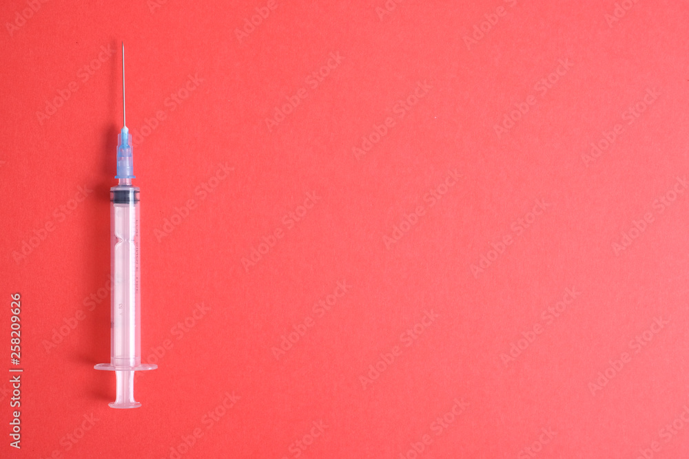 Empty medical syringe on a red background. The concept of dangerous vaccinations. The problem of epidemics from drugs in the twenty first century. Empty medical syringe on a red background. The concept of dangerous vaccinations. The problem of epidemics from drugs in the twenty first century.