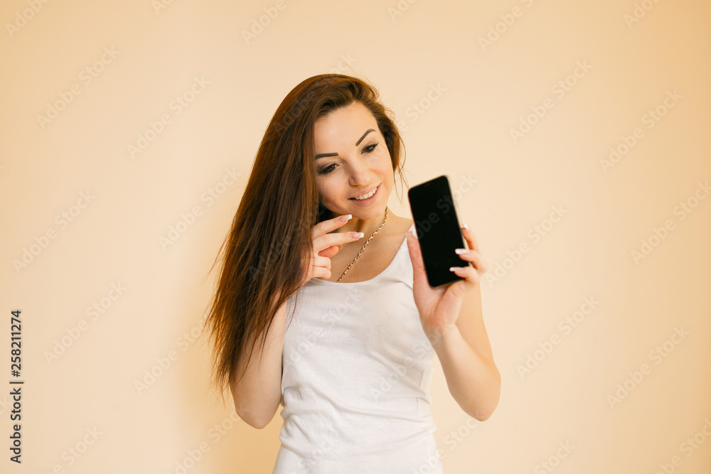 young woman in a white T-shirt chooses an apple, portraits on a uniform beige background young woman in a white T-shirt chooses an apple, portraits on a uniform beige background