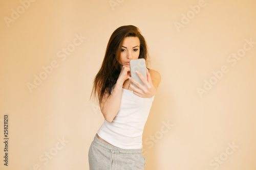  young woman in a white T-shirt chooses an apple, portraits on a uniform beige background