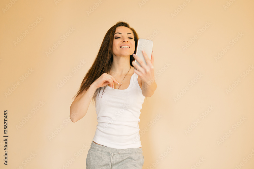 young woman in a white T-shirt chooses an apple, portraits on a uniform beige background young woman in a white T-shirt chooses an apple, portraits on a uniform beige background