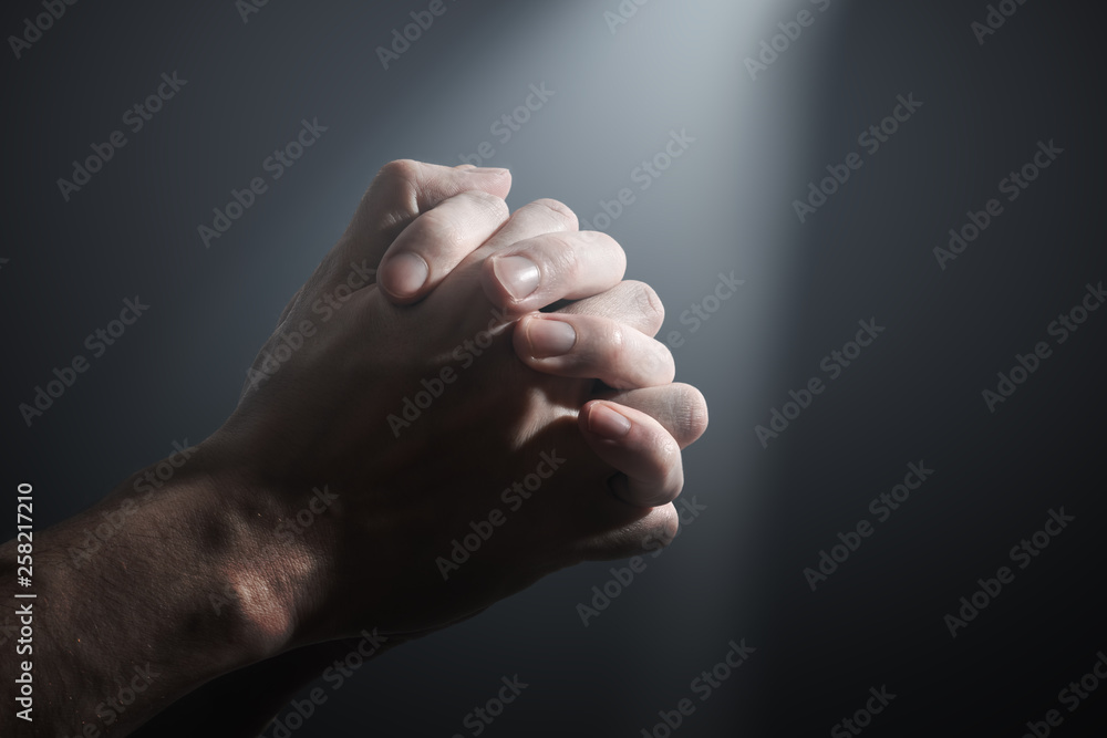 Hands of a prayer. Light shining on praying man's hands. Hands of a prayer. Light shining on praying man's hands.