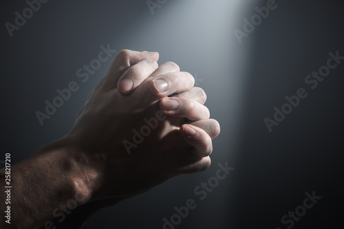 Foto Hands of a prayer.  Light shining on praying man's hands.