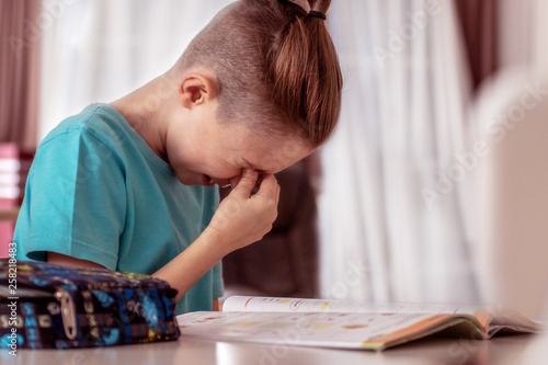 Fotografija Cute schoolboy appearing to be frustrated while doing his homework