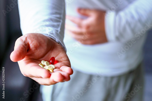 A man holds his stomach, stretches his hand with pills. Health, illness, medicine. Selective focus.