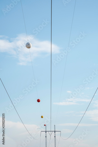 Electric poles with wires and cables set on a bright blue daylight sky.