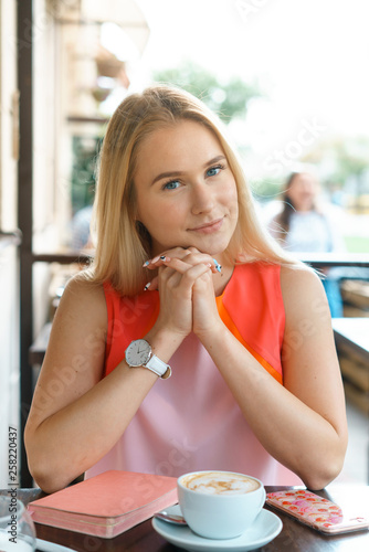 young beautiful blond woman sit at table in cafe drink coffee wait for businesspartner have a business meeting