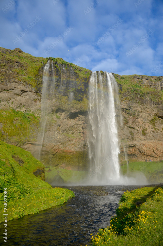 iceland waterfall seljalandsfoss and dark water stream