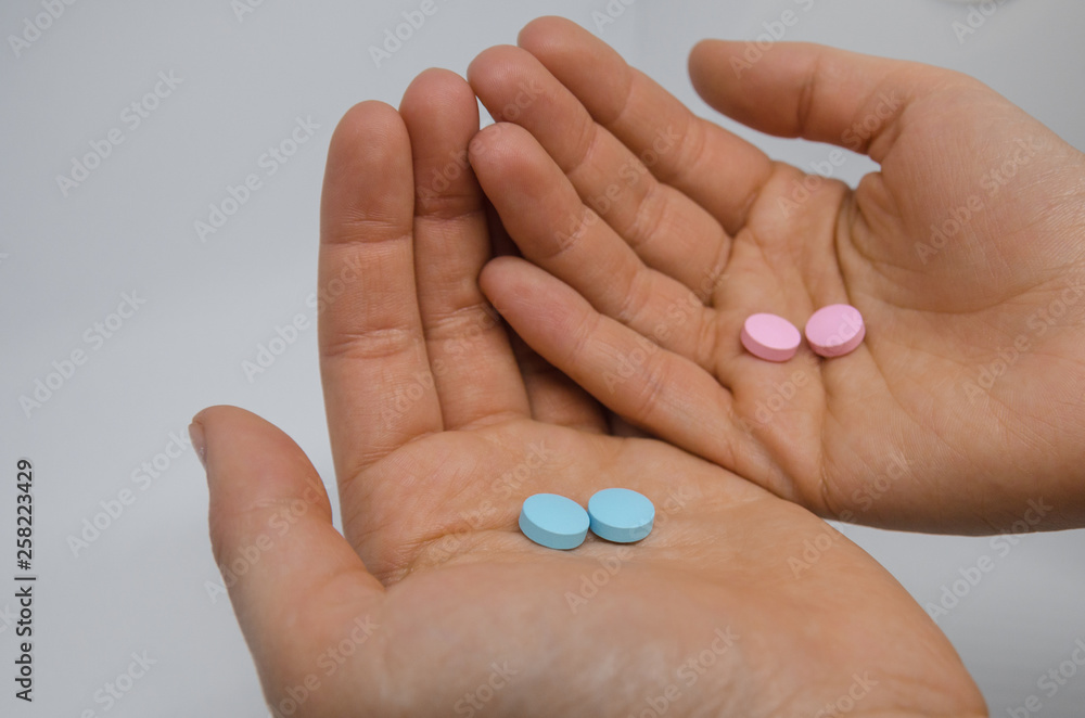 Two hands with pink and blue pills Two hands with pink and blue pills